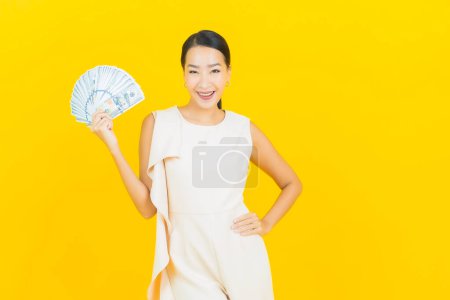 Photo for Portrait beautiful young asian woman smile with a lot of cash and money on yellow color background - Royalty Free Image