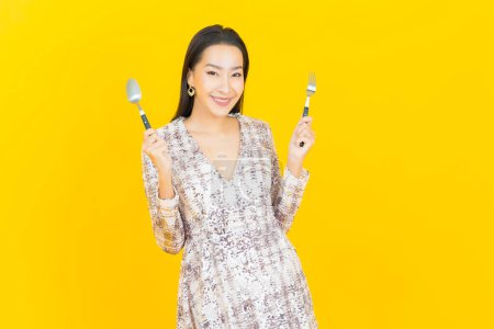 Photo for Portrait beautiful young asian woman smile with spoon and fork on color background - Royalty Free Image