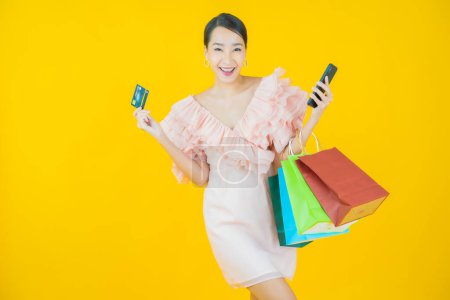 Téléchargez les photos : Portrait belle jeune femme asiatique sourire avec sac à provisions sur fond de couleur - en image libre de droit