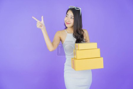 Téléchargez les photos : Portrait belle jeune femme asiatique avec boîte prête pour l'expédition sur fond de couleur - en image libre de droit