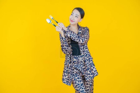 Foto de Retrato hermosa joven asiática mujer sonrisa con cuchara y tenedor en color de fondo - Imagen libre de derechos