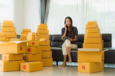 Photo for Portrait beautiful young asian woman with container cardboard parcel box packaging prepare for shipping for customer online shopping in living room - Royalty Free Image