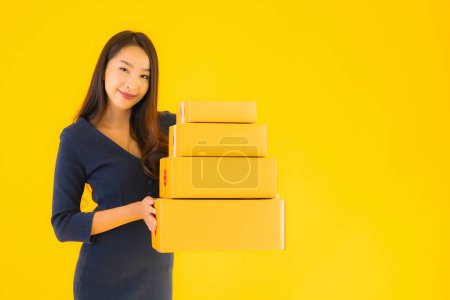 Photo for Portrait beautiful young asian woman with cardboard box packkage ready for shipping on yellow isolated background - Royalty Free Image