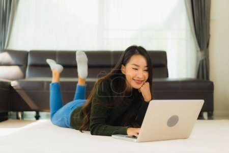 Photo for Portrait beautiful young asian woman use laptop computer with sofa in living room interior - Royalty Free Image