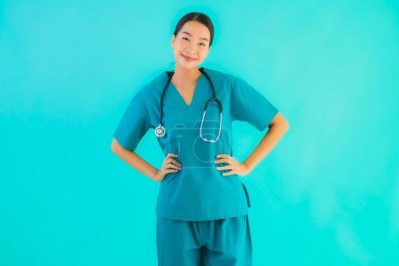 Téléchargez les photos : Portrait belle jeune asiatique médecin femme heureux sourire pour le travail à l'hôpital et clinique sur fond bleu isolé - en image libre de droit