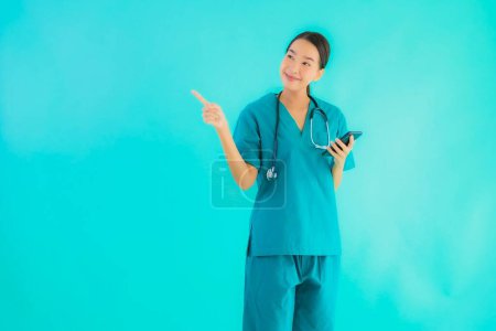 Photo for Portrait beautiful young asian doctor woman show smart mobile phone on blue isolated background - Royalty Free Image