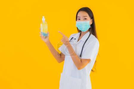 Photo for Portrait beautiful young asian doctor woman wear mask with alcohol gel for protect from covid19 or coronavirus on yellow isolated background - Royalty Free Image