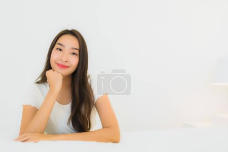 Téléchargez les photos : Portrait belle jeune femme asiatique se détendre sourire heureux sur le lit avec couverture d'oreiller blanc intérieur de la chambre - en image libre de droit