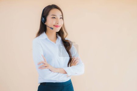 Foto de Retrato hermosa joven asiática mujer de negocios con auriculares para call center en color aislado fondo - Imagen libre de derechos