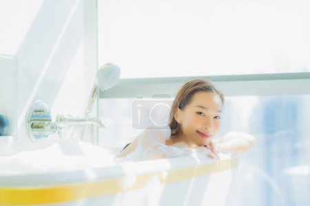 Foto de Retrato hermosa joven asiática mujer relajarse sonrisa disfrutar en bañera en baño interior - Imagen libre de derechos