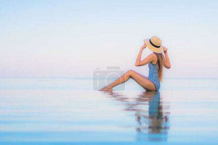 Foto de Retrato hermosa joven mujer asiática relajarse sonrisa ocio alrededor de la piscina al aire libre casi playa de mar en vacaciones de viaje - Imagen libre de derechos