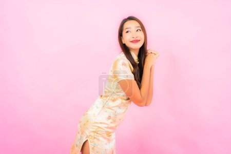 Téléchargez les photos : Portrait belle jeune femme asiatique sourire en action avec le concept de nouvelle année chinoise sur fond de couleur rose - en image libre de droit