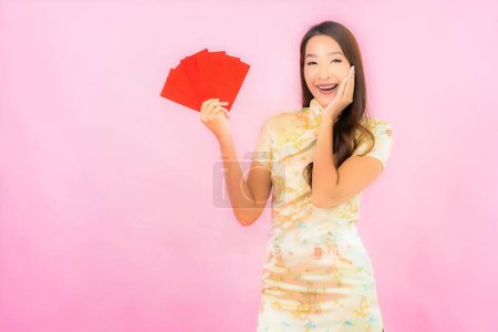 Foto de Retrato hermosa joven mujer asiática con sobres rojos en chino concepto de año nuevo sobre fondo rosa - Imagen libre de derechos