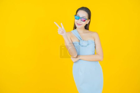 Téléchargez les photos : Portrait belle jeune femme asiatique porter des lunettes 3D sur fond de couleur - en image libre de droit