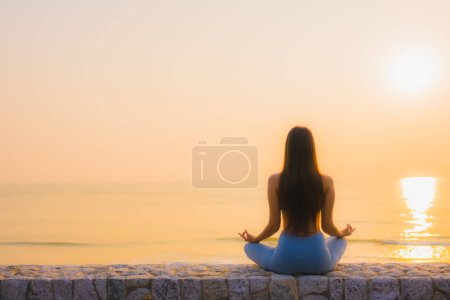 Téléchargez les photos : Portrait jeune femme asiatique faire méditation autour de la mer plage océan au lever du soleil pour la santé - en image libre de droit