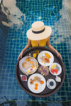 Téléchargez les photos : Portrait belle jeune femme asiatique sourire heureux se détendre avec petit déjeuner flottant autour de la piscine dans la station hôtelière - en image libre de droit