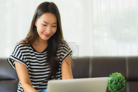 Photo for Portrait beautiful young asian woman using laptop or computer noterbook on sofa for save from coronaviruse or covid19 - Royalty Free Image