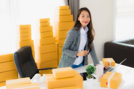 Photo for Portrait beautiful young asian business woman work from home with laptop mobile phone with cardboard box ready for shipping online shopping - Royalty Free Image