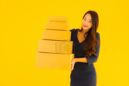 Foto de Retrato hermosa joven asiática mujer con caja de cartón paquete listo para el envío en amarillo aislado fondo - Imagen libre de derechos