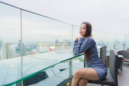 Téléchargez les photos : Portrait belle jeune femme asiatique heureux sourire sur le toit restaurant autour de la ville vue - en image libre de droit