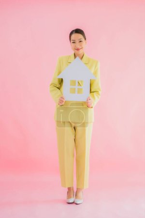 Téléchargez les photos : Portrait belle jeune femme d'affaires asiatique montrer la maison ou signe de maison sur fond isolé couleur - en image libre de droit