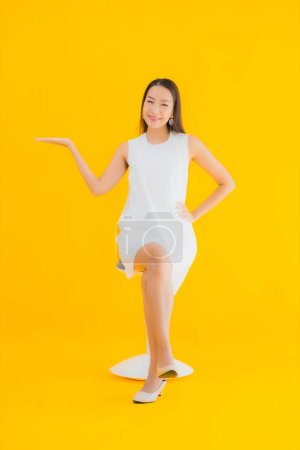 Foto de Retrato hermosa joven asiática mujer en acción sobre amarillo aislado fondo - Imagen libre de derechos