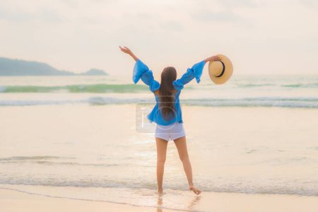 Téléchargez les photos : Portrait belle jeune femme asiatique relax loisirs sourire autour de la plage mer océan au coucher du soleil - en image libre de droit