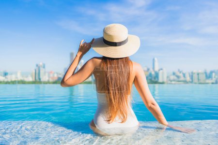 Téléchargez les photos : Portrait belle jeune femme asiatique sourire détendre loisirs autour de la piscine extérieure avec vue sur la ville - en image libre de droit