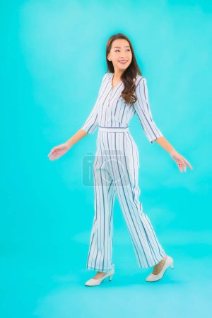 Téléchargez les photos : Portrait belle jeune femme asiatique sourire en action sur fond bleu isolé - en image libre de droit