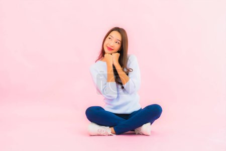 Photo for Portrait beautiful young asian woman sit on floor with pink color isolated background - Royalty Free Image