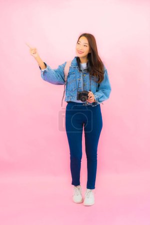 Téléchargez les photos : Portrait belle jeune asiatique femme sac à dos ou bagages avec appareil photo prêt pour Voyage en vacances sur fond rose - en image libre de droit