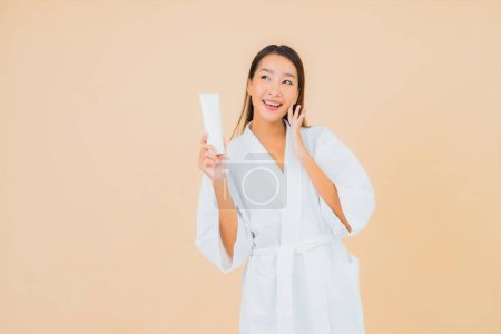 Foto de Retrato hermosa joven mujer asiática con loción de botella y crema facial en color aislado fondo - Imagen libre de derechos