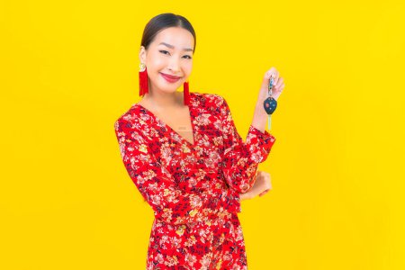 Téléchargez les photos : Portrait belle jeune femme asiatique avec clé de voiture sur fond jaune - en image libre de droit