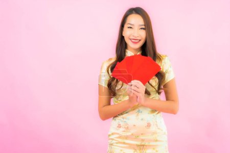 Foto de Retrato hermosa joven mujer asiática con sobres rojos en chino concepto de año nuevo sobre fondo rosa - Imagen libre de derechos
