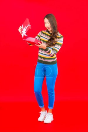 Foto de Retrato hermosa joven mujer asiática con caja de regalo roja sobre fondo rojo - Imagen libre de derechos