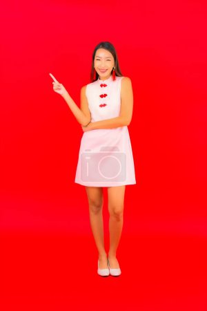 Foto de Retrato hermosa joven mujer asiática desgaste chino nuevo año ropa sobre fondo rojo - Imagen libre de derechos