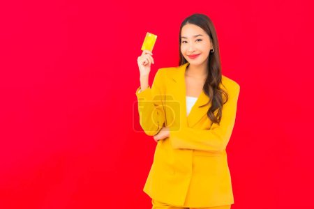 Photo for Portrait beautiful young asian woman use mobile with credit card on red background - Royalty Free Image