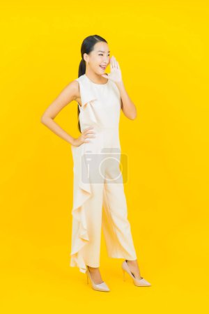 Photo for Portrait beautiful young asian woman smile with action on yellow color background - Royalty Free Image