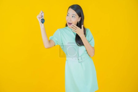 Photo for Portrait beautiful young asian woman smile with car key on yellow color background - Royalty Free Image