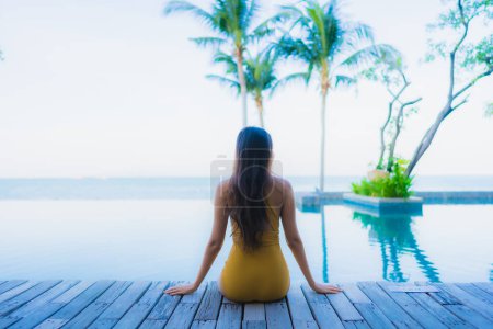 Téléchargez les photos : Portrait belles jeunes femmes asiatiques heureux sourire se détendre autour de la piscine extérieure dans la station hôtelière pour des vacances de voyage - en image libre de droit