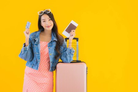 Photo for Portrait beautiful young asian woman with luggage travel bag with passport and boarding pass ticket on yellow isolated background - Royalty Free Image