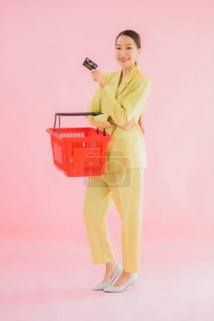 Téléchargez les photos : Portrait belle jeune femme asiatique avec panier d'épicerie du supermarché sur fond de couleur - en image libre de droit