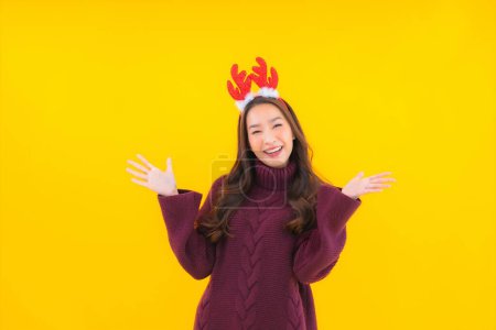 Foto de Retrato hermosa joven asiática mujer desgaste navidad decoración tema en amarillo aislado fondo - Imagen libre de derechos