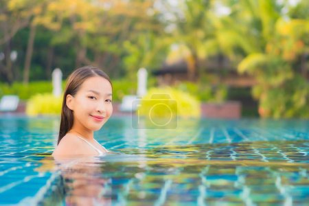 Téléchargez les photos : Portrait belle jeune femme asiatique relax sourire loisirs autour de la piscine extérieure presque mer plage océan pour vacances - en image libre de droit