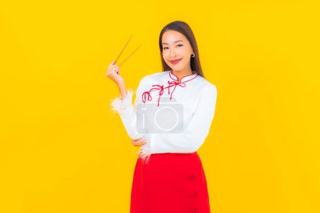 Téléchargez les photos : Portrait belle jeune femme asiatique avec baguette prête à manger sur fond jaune - en image libre de droit