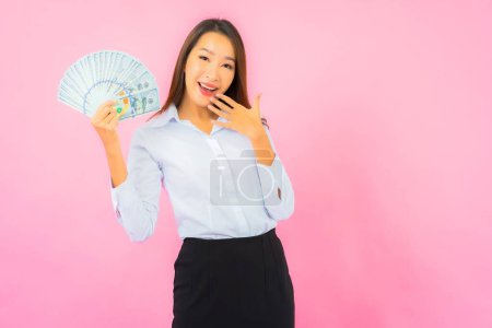 Foto de Retrato hermosa joven asiática mujer con un montón de dinero en efectivo y dinero en rosa fondo - Imagen libre de derechos