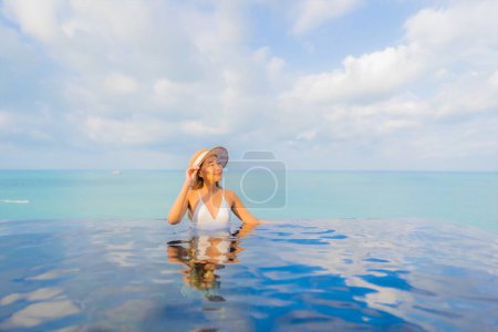 Téléchargez les photos : Portrait belle jeune femme asiatique relax sourire loisirs autour de la piscine extérieure dans la station hôtelière en vacances de voyage - en image libre de droit