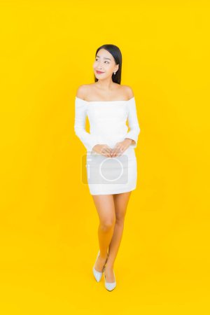 Téléchargez les photos : Portrait belle jeune femme d'affaires asiatique avec sourire et action fond jaune - en image libre de droit