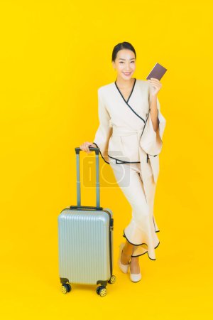 Photo for Portrait beautiful young business asian woman with luggage bag and passport ready for travel on yellow background - Royalty Free Image