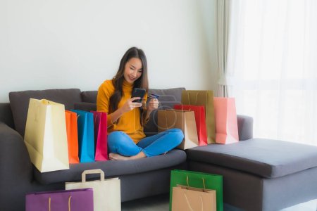 Photo for Portrait young asian woman using laptop computer with smart mobile phone and credit card for online shopping in living room - Royalty Free Image